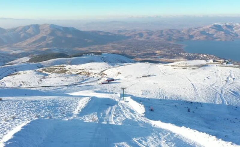 Elazığ’ın Sivrice ilçesindeki göl manzaralı Hazarbaba Kayak Merkezi'nde son haftalarda etkili olan kar, yeni sezon için kayakseverleri umutlandırdı. Hazarbaba Kayak Merkezi’nde Kar Var mı? Hazarbaba Kayak Merkezi’nde kar var.  Geçen sezon yeterli miktarda kar alamaması nedeniyle sezonu açamayan kayak merkezinde kasım sonu itibarıyla etkili olan yağışla, kar kalınlığı ortalama 30 santimetreye ulaştı. "Doğu'nun saklı denizi" olarak adlandırılan Hazar Gölü manzarasıyla da ilgi gören kayak merkezinde yeni sezon için yürütülen bakım ve yenileme çalışmaları tamamlanma noktasına gelirken, sezonun açılabilmesi için 15-20 santimetre daha kar bekleniyor. Hazarbaba Dağı'nın eteklerinde 2 bin 300 rakımda yer alan kayak merkezi, 1300 metrelik dikey ve 6 kilometrelik yatay pist alanı ile ziyaretçilerine kızak, kayak, snowboard, kar motoru, göl manzaralı restoran ve kafeterya imkanlarıyla hizmet veriyor. - "Yeterli kar yağışıyla beraber sezonu açacağız" Hazarbaba Kayak Merkezi yetkilisi İsmet Berkay Altundaş, AA muhabirine, ziyaretçilere en iyi hizmeti sunmak adına sezon hazırlıklarını titizlikle yürüttüklerini, mevcut imkanları daha da geliştirdiklerini söyledi. Geçen haftalarda yağışla kar kalınlığının 25-30 santimetreye ulaştığını ifade eden Altundaş, "Özellikle zirve kısmında daha fazla kar kalınlığına ulaştık. Kayak sezonunu tam anlamıyla açabilmemiz adına 40 ila 50 santimetre arasında kar kalınlığına ihtiyacımız var. Önümüzdeki günlerde yoğun kar yağışı bekliyoruz." dedi. Sezon öncesinde gerekli bakım çalışmalarını yaptıklarını, tesiste eksikliğin bulunmadığını kaydeden Altundaş, "Tek eksiğimiz kar. Umarım ilerleyen günlerde yeterli kar yağışıyla beraber sezonu açacağız." ifadesini kullandı. Altundaş, bu yıl erken yağan karla son 10 senenin en uzun kayak sezonunu geçirmeyi umduklarını dile getirerek, şöyle devam etti: "Yeni sezonda ziyaretçilerimiz için üç noktada hizmet veriyoruz. Bir noktamızda kayak ekipmanları kiralama ve sıcak içecek satışımız mevcut. Bir üst istasyonumuzda, sucuk ekmek, köfte ekmek, sıcak içecekler, meşrubatlar gibi yiyecek ve içecek hizmetimiz var. En üst istasyonumuzda, bu yıl yenilediğimiz, 250 metrekareye yakın büyütme yaptığımız hem günübirlik tesis hem de 12 ay hizmet verecek alakart restoranımızı faaliyete alıyoruz. İnşallah yılbaşından önce açılışını yapacağız. Ziyaretçilerimize cam konseptli, göl manzarasını kesintisiz izleyebilecekleri bir yer sunuyoruz." - "En büyük özelliği iki göl manzarası olması" Altundaş, merkezde profesyonel, acemi, macera ve baby-lift olmak üzere 4 pist ve teleski bulunduğunu bildirdi. Merkezde ziyaretçilerin eşsiz manzara eşliğinde kayak yapmanın keyfini çıkardığını anlatan Altundaş, şunları kaydetti: "Hazarbaba Kayak Merkezi'ni diğerlerinden ayıran en büyük özelliği, iki göl manzarası olması. İlk aşamada Hazar Gölü, onun arkasında Keban Baraj Gölü manzarasını seyredebiliyorsunuz. Hava sisli olmadığı takdirde, kayakseverler kayarken iki gölü de görebilme şansına sahip. Ayrıca buradaki kristal kar özelliği, kayak tutkunlarının yine vazgeçilmezi. Geniş bir pist alanımız var. Tüm ziyaretçilerimizi kar keyfi için bekliyoruz." Altundaş, karla kaplı merkezde ziyaretçiler için kızak hizmeti de vermeye başladıklarını sözlerine ekledi.